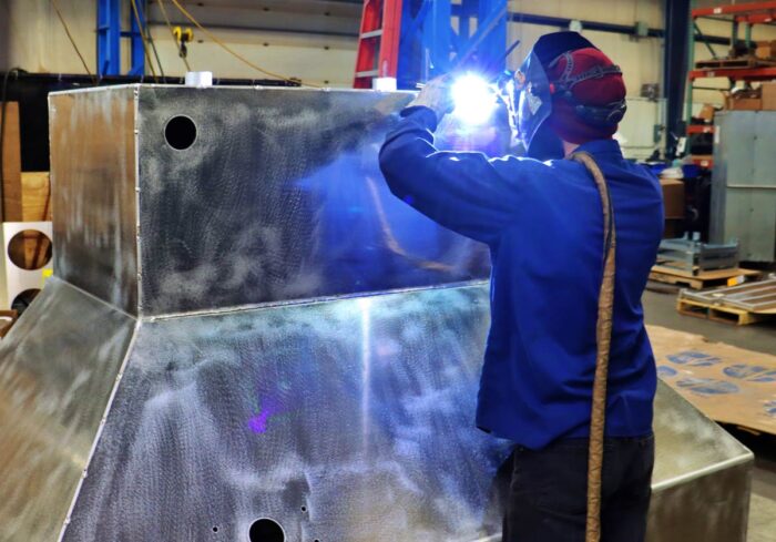 man welding the top of a large metal container